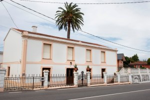 Sencilla casa situada al pie de la carretera que se dirige a Oleiros, a las afueras de Sada. El espacio, de planta rectangular y dos alturas, se abre en la fachada principal con ocho vanos recercados, los de la planta baja con acodos.