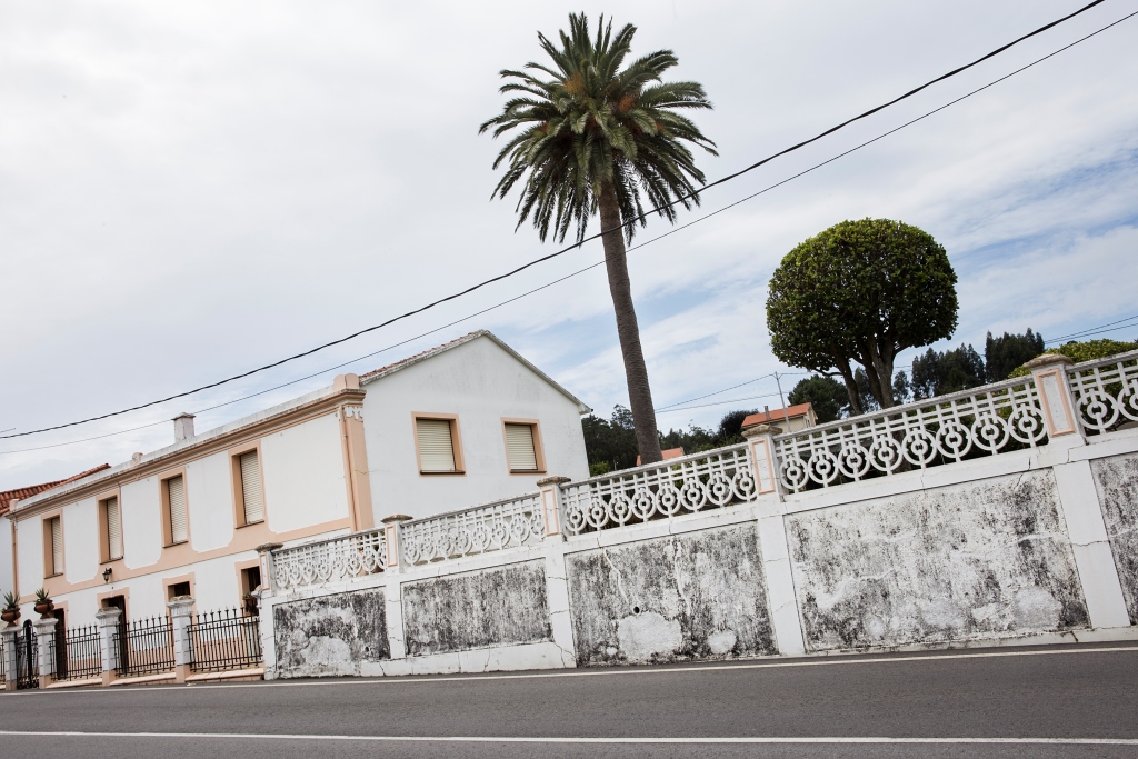 Sencilla casa situada al pie de la carretera que se dirige a Oleiros, a las afueras de Sada. El espacio, de planta rectangular y dos alturas, se abre en la fachada principal con ocho vanos recercados, los de la planta baja con acodos.